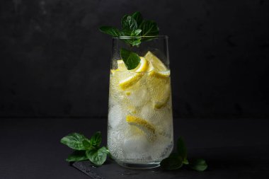 Siyah arka planda taze bir kokteyl. Buzlu ve limonlu meşrubat. Soğuk içecek.