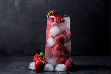 Siyah arka planda çilekli ve buzlu kokteyl. Tazeleyici içecek..