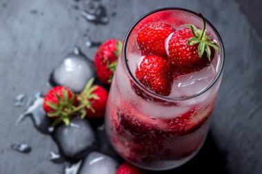 Siyah arka planda çilekli ve buzlu kokteyl. Tazeleyici içecek..