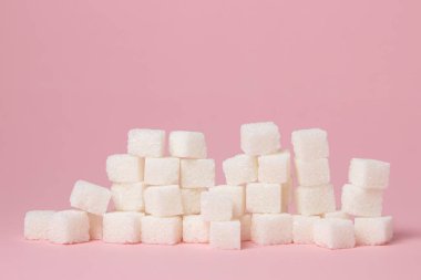 Pembe arka planda küp şekerler. Aşırı şeker tüketimi