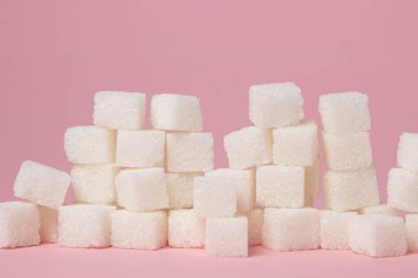 Pembe arka planda küp şekerler. Aşırı şeker tüketimi