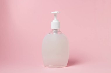 Pembe arka planda bir şişe beyaz sıvı sabun. Kişisel hijyen. Temizlik aracı