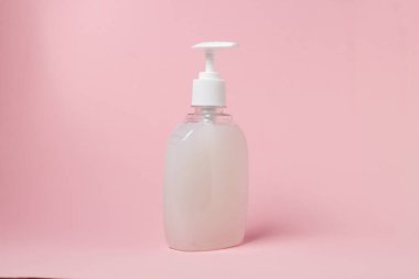 Pembe arka planda bir şişe beyaz sıvı sabun. Kişisel hijyen. Temizlik aracı