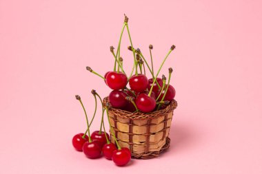 Pembe arka planda bir sepetin içindeki kiraz. Taze kiraz. yaz meyvesi