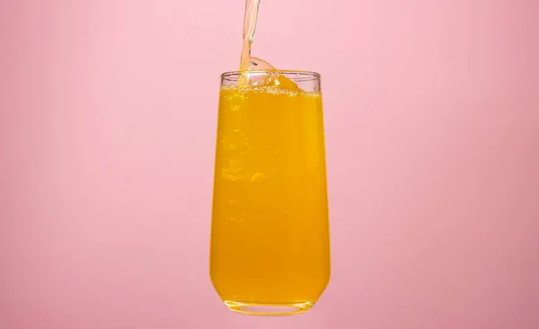 粉红背景的果汁橙汁倒入杯子里 味道鲜美的饮料 — 图库照片