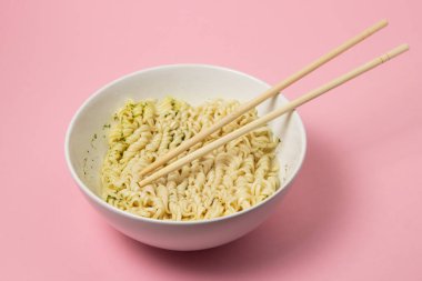 Pembe arka planda haşlanmış hazır şehriye. Fast food. Modern yemek..