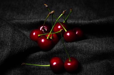 Siyah kumaşta kırmızı kiraz. Yemek fotoğrafı gösterişsiz. tatlı meyve