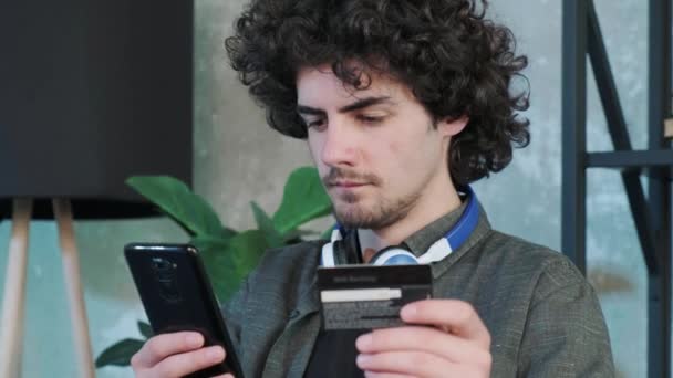Молодий чоловік купує онлайн з кредитною карткою за допомогою смартфона вдома . — стокове відео