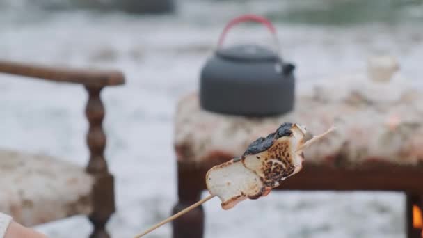 Kobieta trzymająca pieczone pianki i metalową filiżankę herbaty. — Wideo stockowe