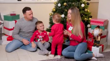 Mutlu aile Noel ağacının yanında eğleniyor ve birlikte oynuyorlar..