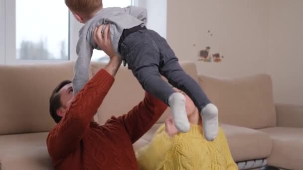 Jovens pais felizes estão sorrindo, abraçando e brincando com seu filho. — Vídeo de Stock