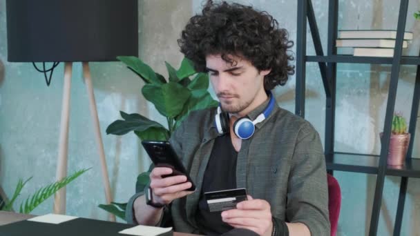 Mladý muž nakupování on-line s kreditní kartou pomocí chytrého telefonu doma. — Stock video