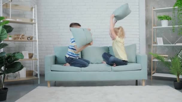 幸せな双子の子供2人が枕で家で戦っています。楽しみ方. — ストック動画