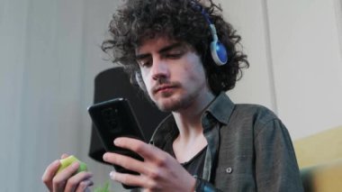 Genç adam elma yerken müzik dinliyor ve dans ediyor..