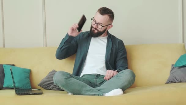 Buona giornata di svago a casa. Giovane barbuto gioioso che parla al cellulare. — Video Stock