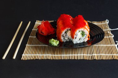Popüler yemek. Suşi, siyah beton arka planda siyah bir tabakta zencefil turşusu. Japon usulü servis edilmiş. Yukarıdan rulo kenarlı suşi çubuğu tabağı..