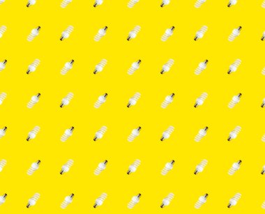 Enerji tasarrufu kavramı. Sarı arka planda floresan lambaların kusursuz deseni.