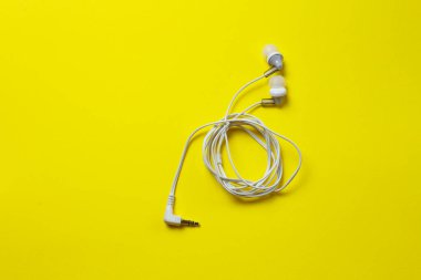 Sarı arka planda kablolu kulaklıklar..