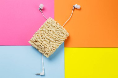 Şaka fotoğrafı. Hazır erişte, çok renkli bir arka planda karışık bir kulaklık telini sembolize eder..