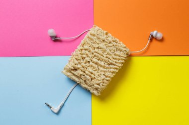 Şaka fotoğrafı. Hazır erişte, çok renkli bir arka planda karışık bir kulaklık telini sembolize eder..