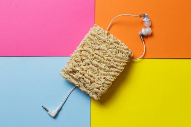 Şaka fotoğrafı. Hazır erişte, çok renkli bir arka planda karışık bir kulaklık telini sembolize eder..