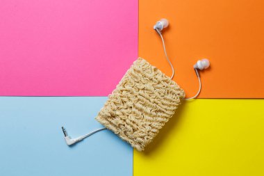 Şaka fotoğrafı. Hazır erişte, çok renkli bir arka planda karışık bir kulaklık telini sembolize eder..