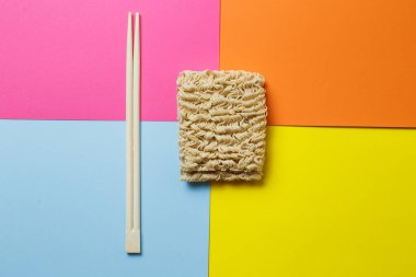 instant noodles and chopsticks on a bright trendy background.