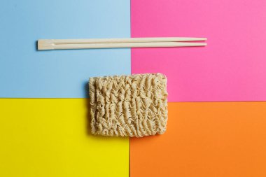 instant noodles and chopsticks on a bright trendy background.