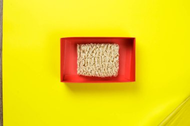 Sarı arka planda kırmızı kutuda çiğ erişte..