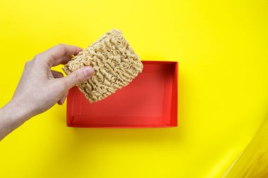 Hazır erişteyle el ele tutuşmak. Çiğ erişte ve sarı arka planda kırmızı bir kutu..