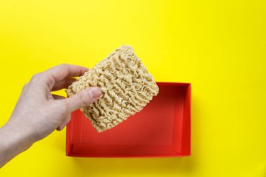 Hazır erişteyle el ele tutuşmak. Çiğ erişte ve sarı arka planda kırmızı bir kutu..