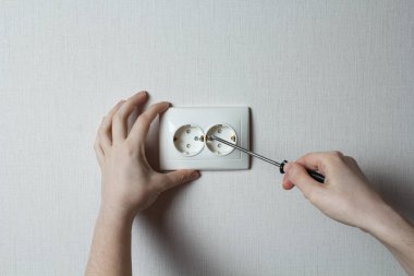 the girl installs the socket in the wall. home renovation. Do-it-yourself repair concept.