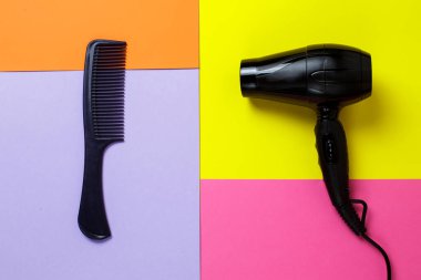 Tarak ve saç kurutma makinesi çok renkli bir arka planda yatıyor. Modaya uygun parlak renkler. stilist ekipmanları.