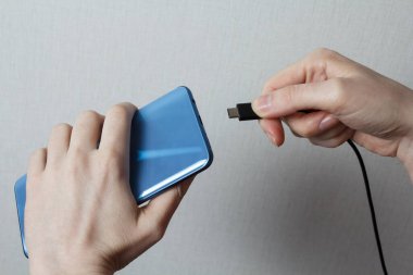 Kız cep telefonunu şarj cihazına bağlıyor..