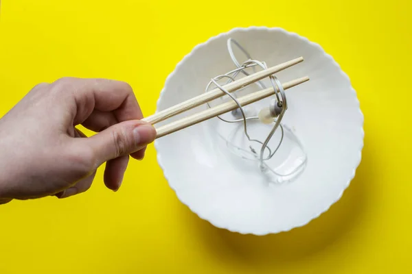 Female Hand Holds Headphones Chopsticks Plate Headphone Wires Symbolize Noodles — Stock Fotó