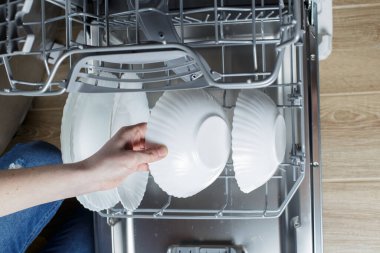 clean dishes in the dishwasher basket. Cleaning the house and washing dishes in the dishwasher.