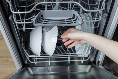 clean dishes after washing. the wife gets dry and clean dishes from the dishwasher.