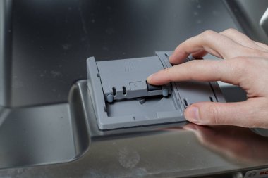 Kız tableti bulaşık makinesine yüklüyor. Bulaşık makinesini aç.