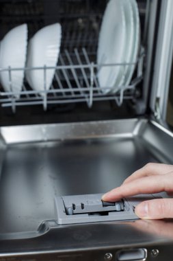 Kız tableti bulaşık makinesine yüklüyor. Bulaşık makinesini aç.