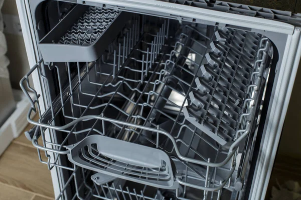 open dishwasher. the hostess is preparing to load dirty dishes into the dishwasher.