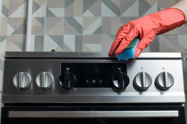 a woman in red rubber gloves cleans a gas stove. cleaning in the kitchen.