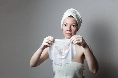 Kızın elinde kozmetik çarşaf maskesi var..