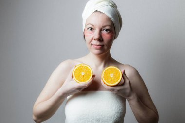 Güzel bir kadın göz bandı kullanır. Gülümseyen ve elinde portakalın iki yarısı olan bir kadın.