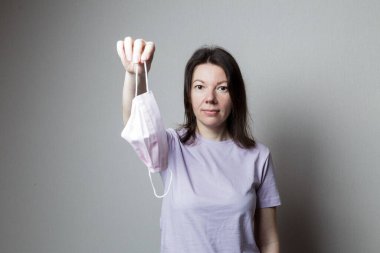 Çekici bir kadın elinde maske tutuyor. Karantinanın sonu kavramı