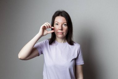 Elinde hap tutan güzel bir kadın. Kız bir hap yutacak. kırmızı hap elinde.