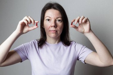 Güzel bir kız elinde iki kırmızı hap tutuyor.