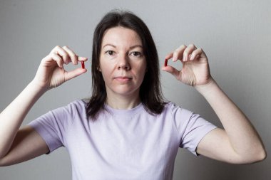 Güzel bir kız elinde iki kırmızı hap tutuyor.