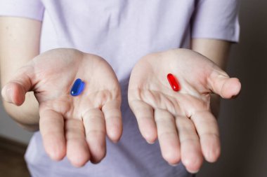 Kırmızı ve mavi haplar. Elinde kırmızı ve mavi haplar tutan bir kız.