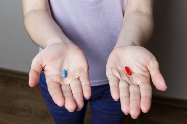 Kırmızı ve mavi hap kadın elinde.