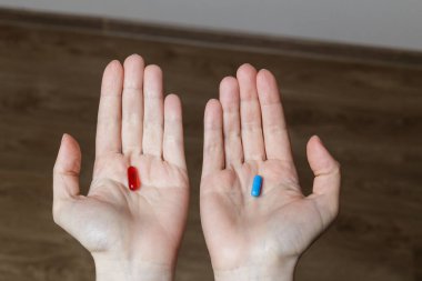 Kırmızı ve mavi hap kadın elinde.